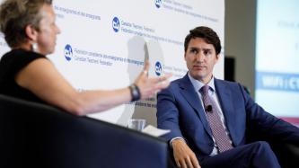 PM Trudeau listens to a woman speak on stage