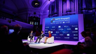 PM Trudeau, PM Mark Rutte of the Netherlands, and a woman sit on a stage