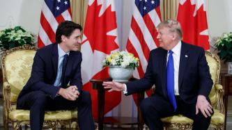 President Trump sits gesturing towards Prime Minister Trudeau