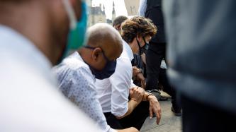 PM Trudeau and Minister Hussen kneel in a crowd