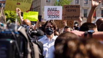 PM Trudeau stands among protestors holding up signs