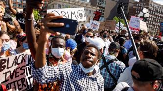 Protesters hold signs and smartphones up in a crowd 