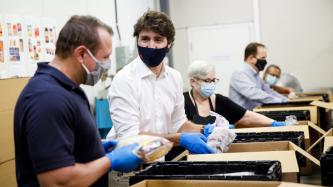 PM Trudeau and MP MacKinnon sort food with volunteers