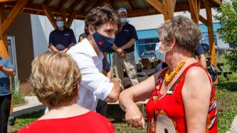Le PM Trudeau salue un bénévole d’un coup de coude Woman: Le PM Trudeau salue une bénévole d’un coup de coude