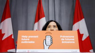 La Dre Tam derrière une affiche sur l’application Alerte COVID