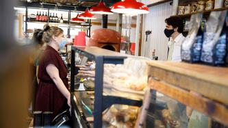 A woman stands at a food counter with PM Trudeau on the opposite side