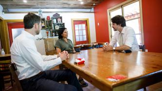 PM Trudeau, MP Amos, and a woman sit at a table