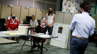 Le PM Trudeau est debout à côté d’un groupe de femmes à leur poste de travail