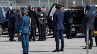 Le PM Trudeau et des dignitaires regardent les proches de militaires se tenir les uns les autres