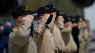 Military members stand in a line in salute position
