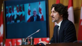 Le PM Trudeau, devant un micro, est joint virtuellement par la VPM Freeland et le ministre Blair