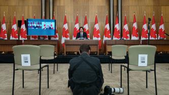 Photographer at work in front of PM Trudeau, DPM Freeland and Minister Blair are on a screen