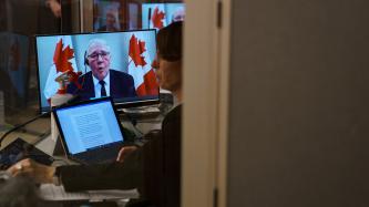 Woman at work with a tablet with Minister Bill Blair on a screen