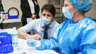 A nurse shows a syringe to PM Trudeau