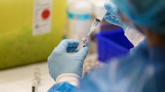 A nurse prepares a dose of vaccine against COVID-19