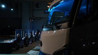 An electric truck is parked next to the panelists