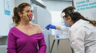 Sophie Grégoire Trudeau looks on as a woman in a white cloak administers a needle to her arm