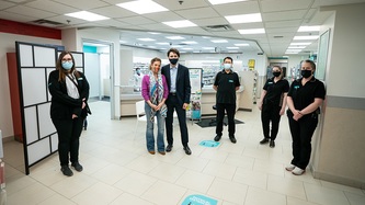 PM Trudeau with his wife and others in black uniform stand socially distanced from one another