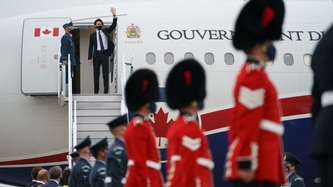 Prime Minister Trudeau  waves from the entrance of a plane
