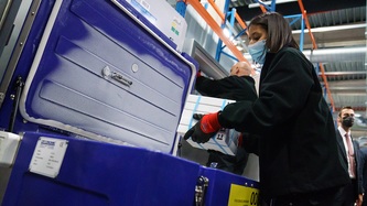 A woman places boxes of vaccines in a medical cooler