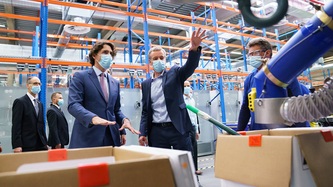 Prime Minister Trudeau and a man are observing manufacturing equipment