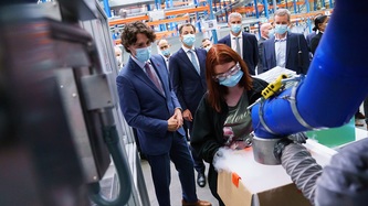 Prime Minister Trudeau looks at an employee operating manufacturing equipment