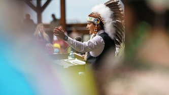 Cowessess First Nation Chief Cadmus Delorme motions with his arm at a podium