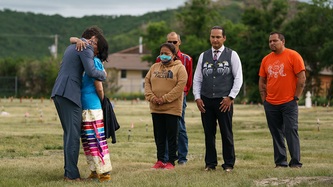 PM Trudeau and a woman embrace as Cowessess First Nation Chief Cadmus Delorme and others look on