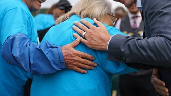 Prime Minister Justin Trudeau and another man’s hand are on the shoulder of a woman