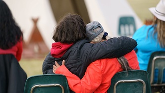 Two people sit and lean in an embrace