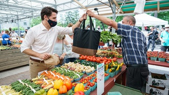 A market vendor hands a bag to Prime Minister Trudeau
