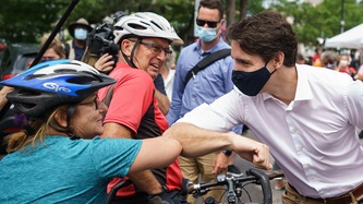 Le premier ministre Trudeau et une cycliste se saluent avec le coude