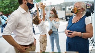 Prime Minister Trudeau talks with a woman while Ella-Grace and Hadrien play together