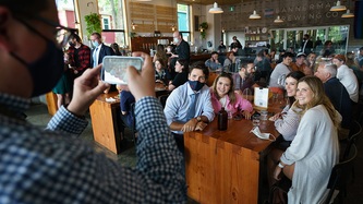 Quelqu'un tient un téléphone, le PM Trudeau et d’autres personnes qui sourient à une table