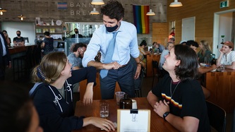 PM Trudeau exchanges an elbow bump with a woman seated at a table with others