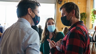 Le PM Trudeau et un homme se regardent tandis qu’une femme tient un bébé dans ses bras