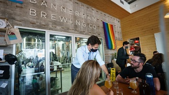 Le PM Trudeau s’appuie sur une table où deux personnes assises le regardent.