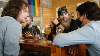 Two men look to PM Trudeau leaning elbows on their table