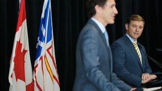 Premier Furey anPM Trudeau stand at podiums with a national and provincial flag behind them