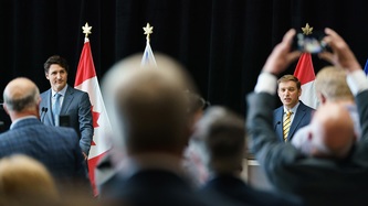 A view from behind a crowd of Premier Furey and PM Trudeau at podiums
