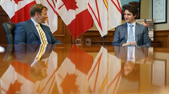Premier Furey and PM Trudeau look to one another at the end of a large table