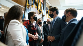 PM Trudeau and a woman look to one another as others stand in a row nearby