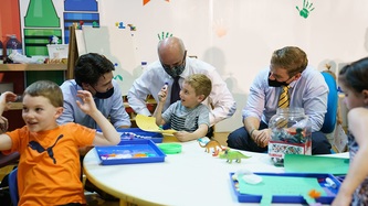 PM Trudeau and others sit with children who play