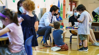 PM Trudeau sits at a small table where children play