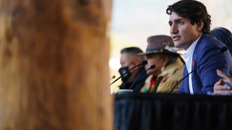 Prime Minister Justin Trudeau sits facing mics