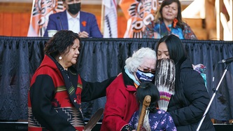 Women and a child hug each other as PM Trudeau and Chief Casimir look on
