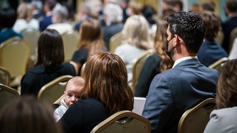 Une femme dans l'assistance tient son bébé dans ses bras