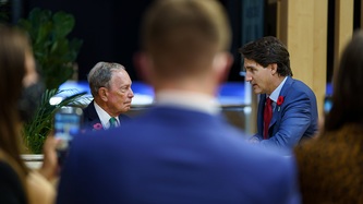 Michael Bloomberg and PM Trudeau are in view through a crowd looking on