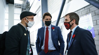 Minister Guilbeault faces a man in a hallway as PM Trudeau looks on