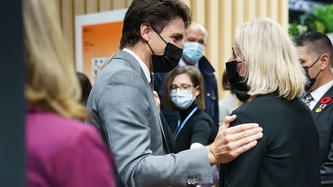 Prime Minister Justin Trudeau stands facing someone with his hand on their shoulder